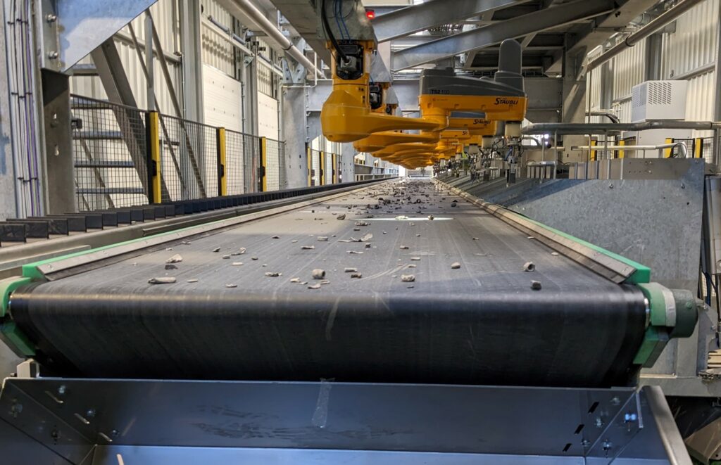 Row of robots above a conveyor carrying sorted metal pieces on a Matvision line